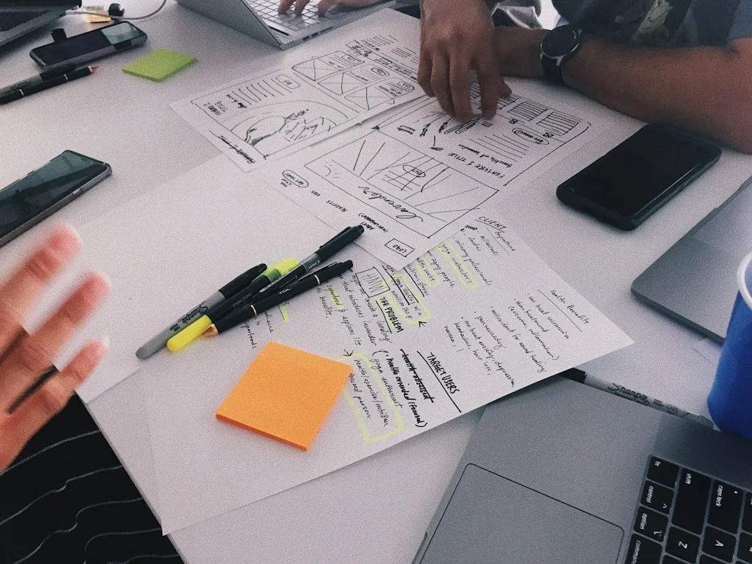 Vue de dessus d’une équipe qui collabore avec des ordinateurs portables, des téléphones et des notes dans un bureau moderne.